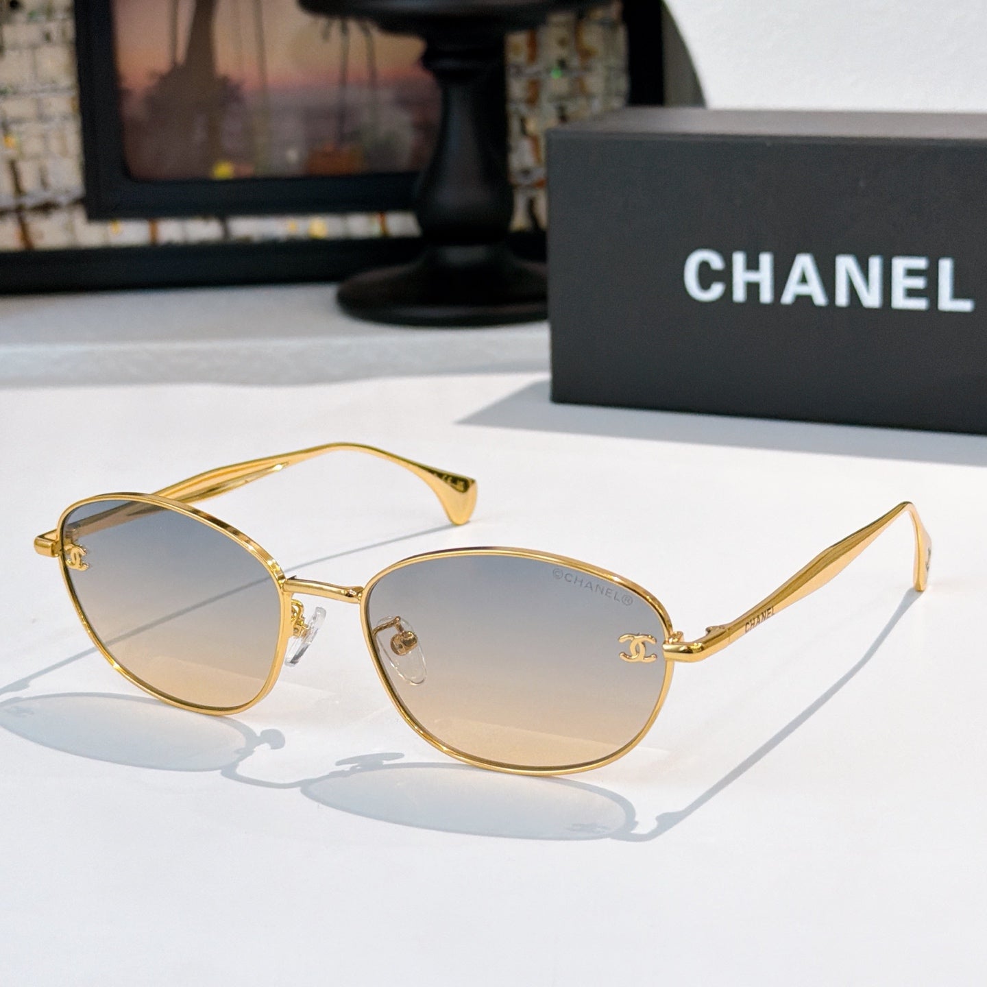 Sunglasses with gold-tone frame and light gray tinted lenses, oval shape