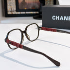 Chanel eyeglasses side view with black frame, burgundy strap-style temple, clear lens.