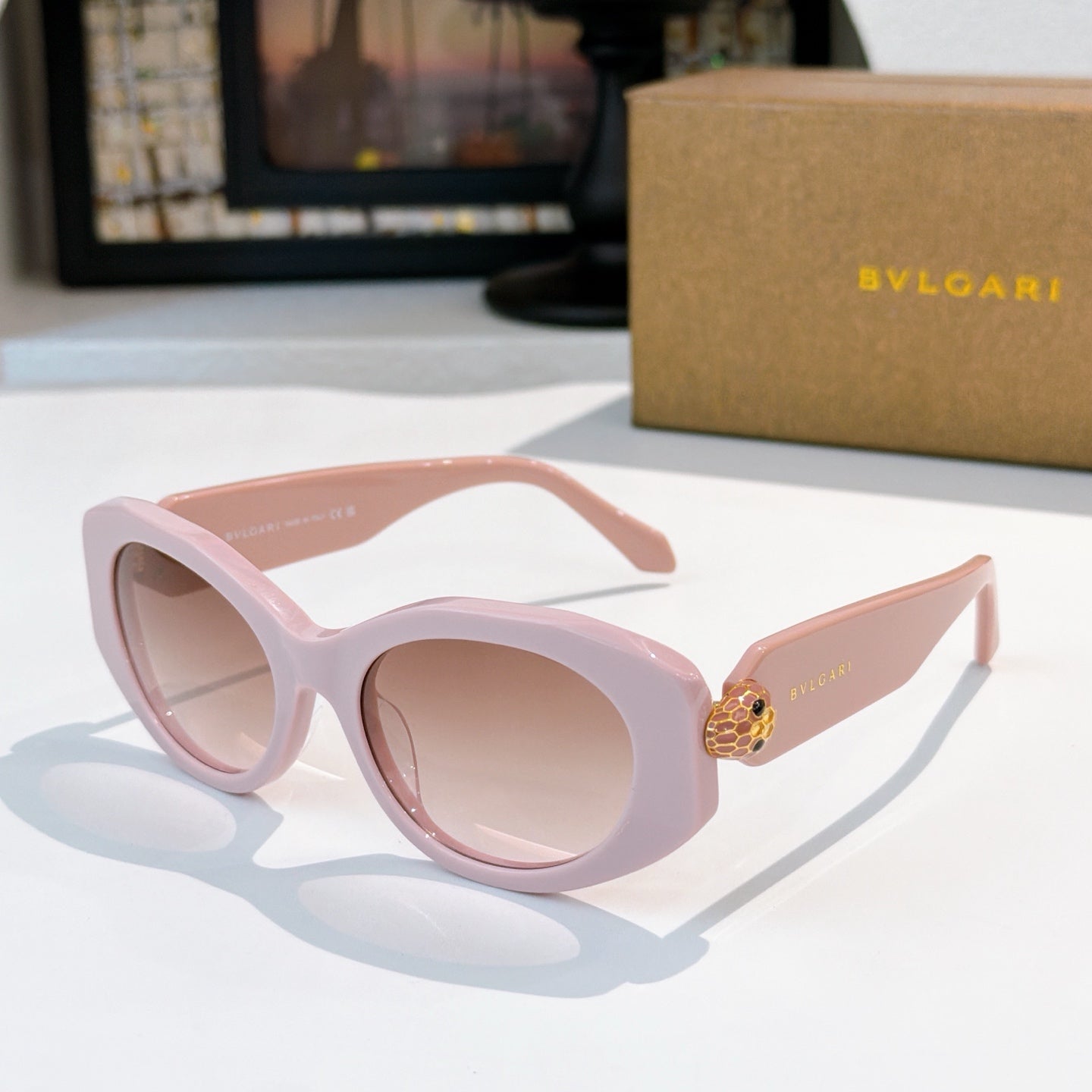 Pink Bvlgari round-frame sunglasses with gold logo temple detail and pale pink lenses