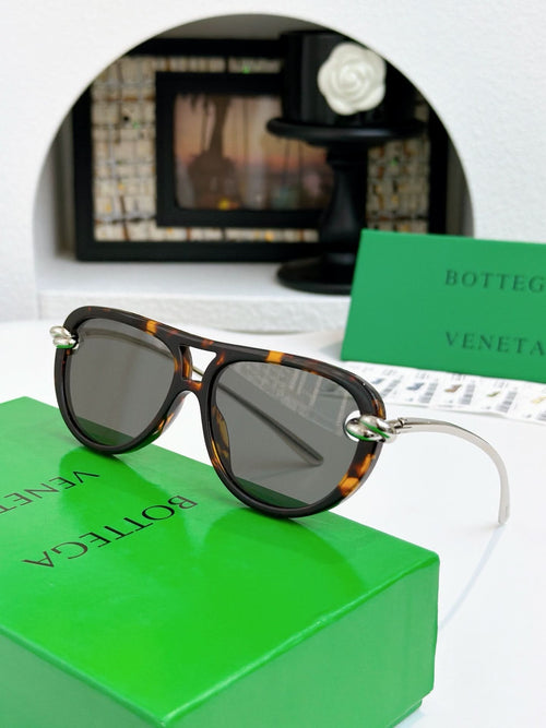 Sunglasses with tortoise-pattern frame and gold-tone accents, dark tinted lenses.