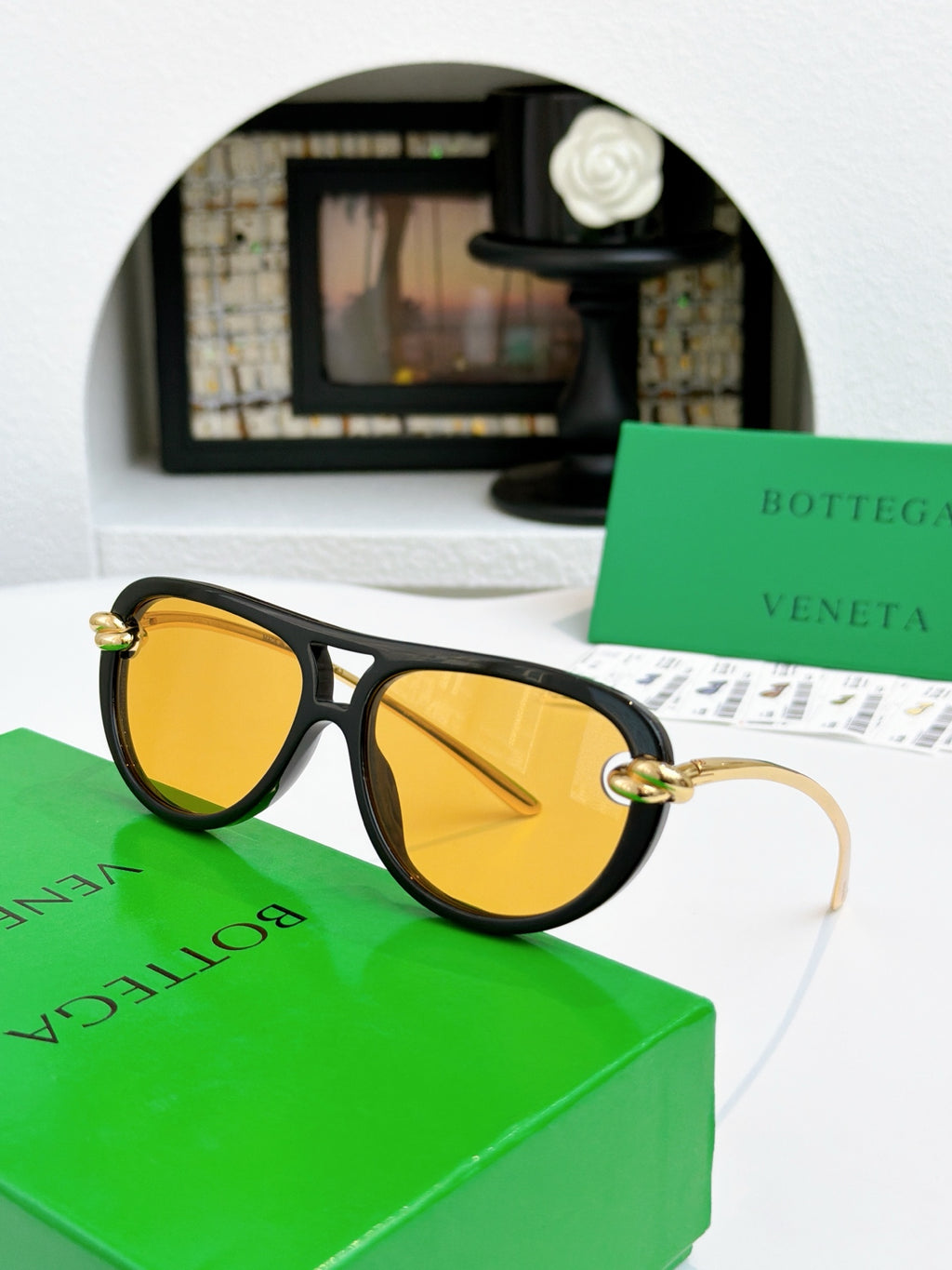 Sunglasses with black frame and gold-tone accents, yellow-tinted lenses.