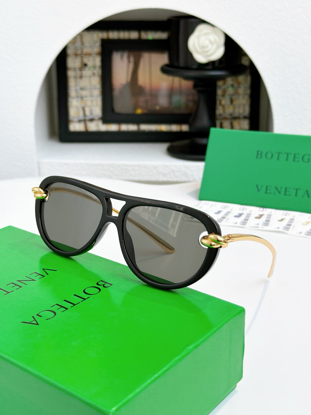 Sunglasses with black frame and gold-tone accents, dark tinted lenses.