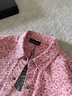 Pink patterned long-sleeve shirt with black brand tag at collar and buttons