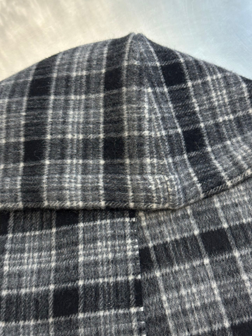 Plaid poncho neckline with stitched seam and small button detail