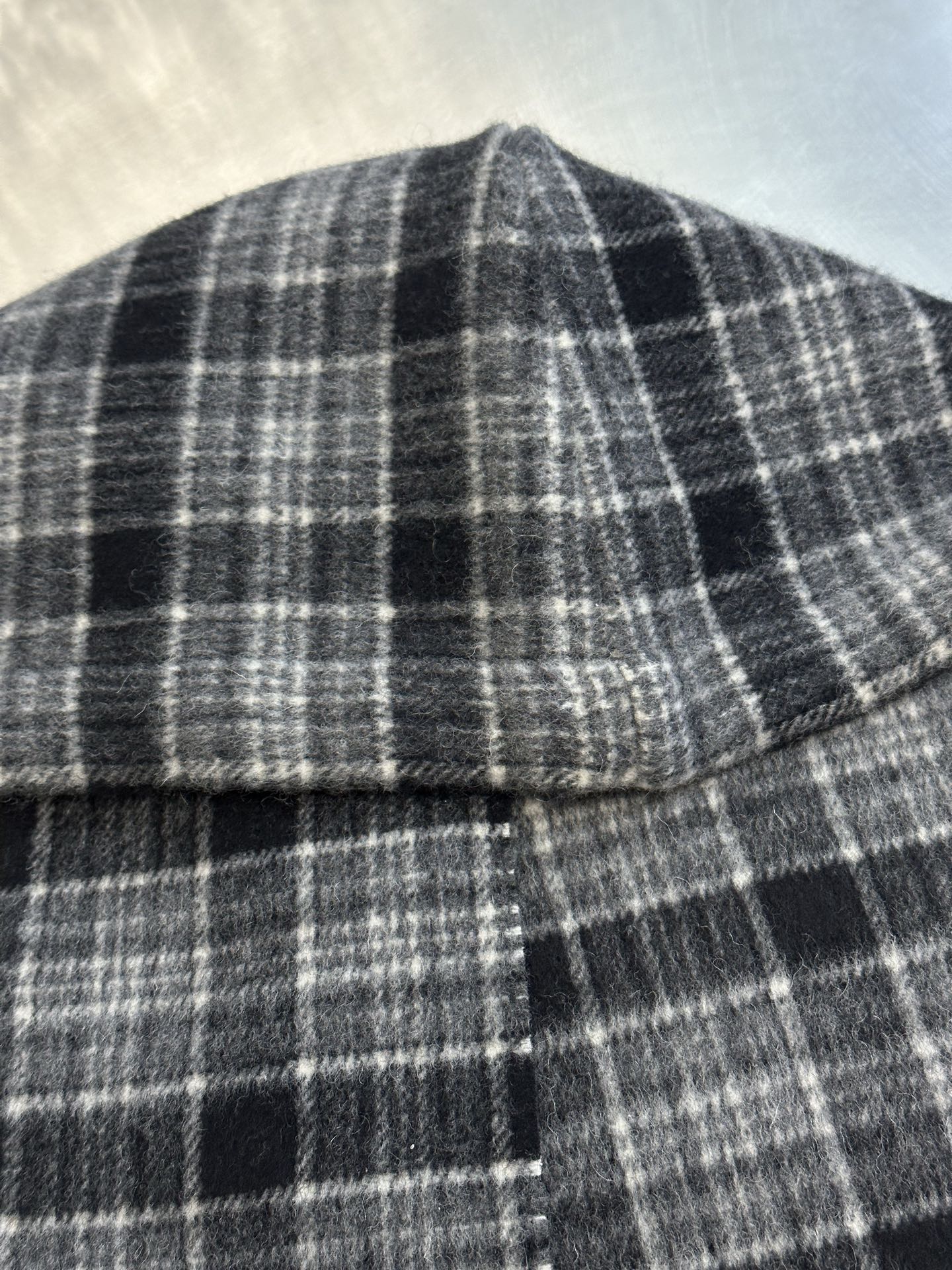 Plaid poncho neckline with stitched seam and small button detail