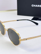 Side view of round sunglasses with gold frame and dark lenses
