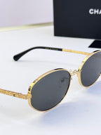 Close-up of round sunglasses with gold frame and dark gray tinted lenses
