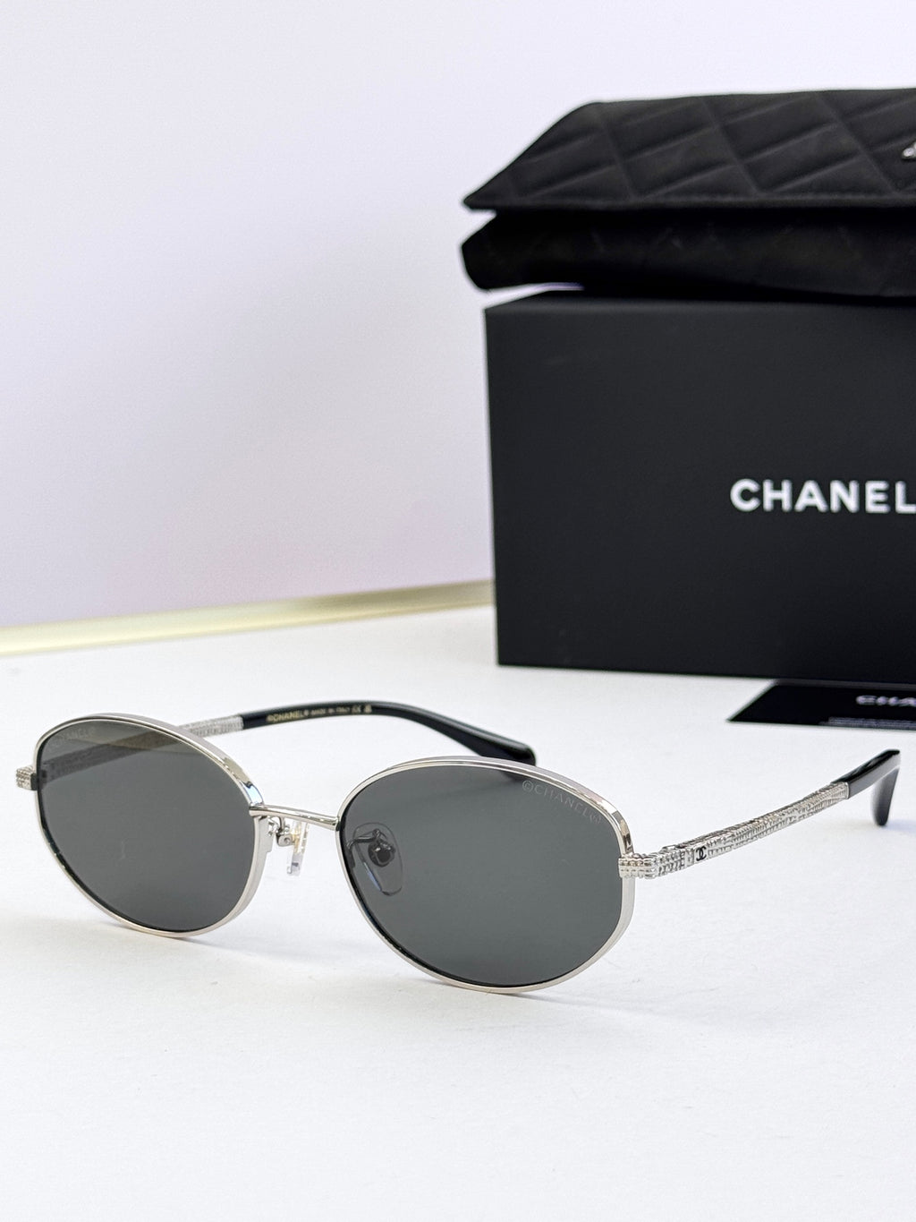 Round sunglasses with silver frame and dark gray lenses, side profile view