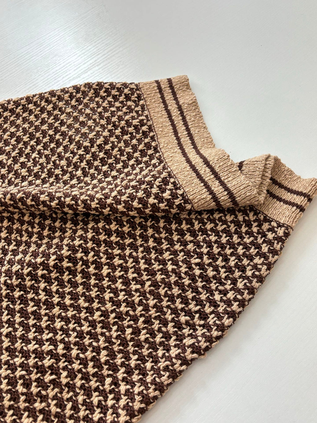 Knit polo shirt sleeve and hem edge with tan striped cuff and patterned knit