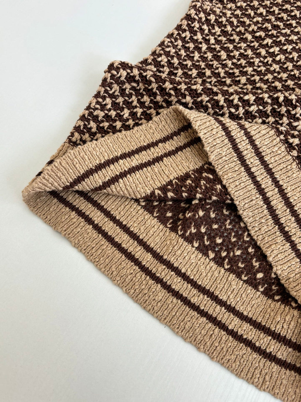 Knit polo shirt cuff close-up with brown patterned knit and tan striped trim