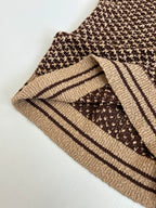 Knit polo shirt cuff close-up with brown patterned knit and tan striped trim