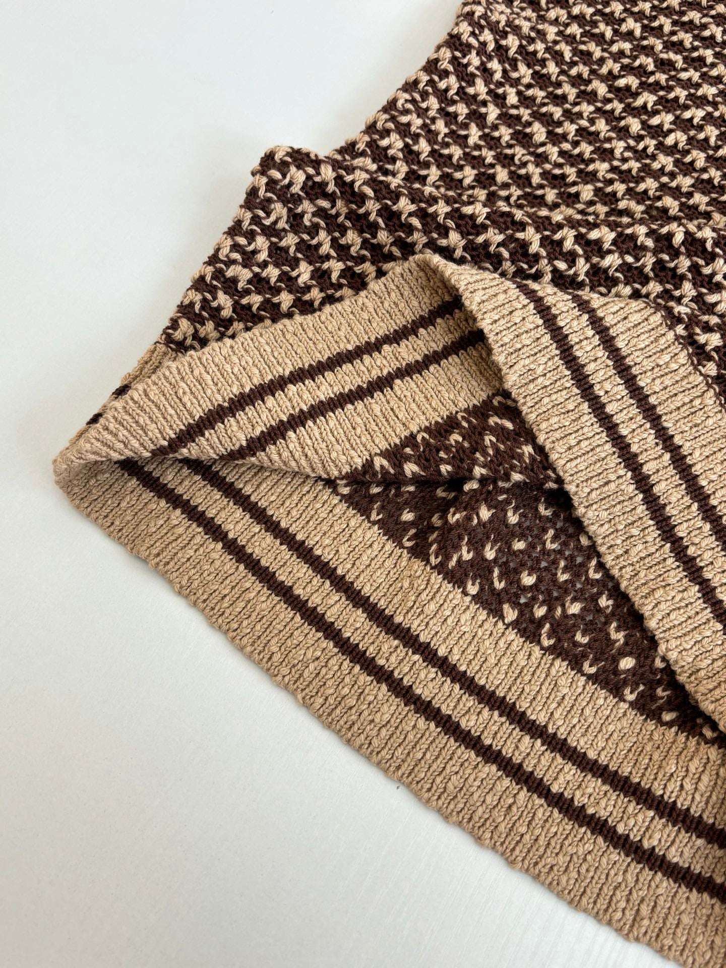 Knit polo shirt cuff close-up with brown patterned knit and tan striped trim