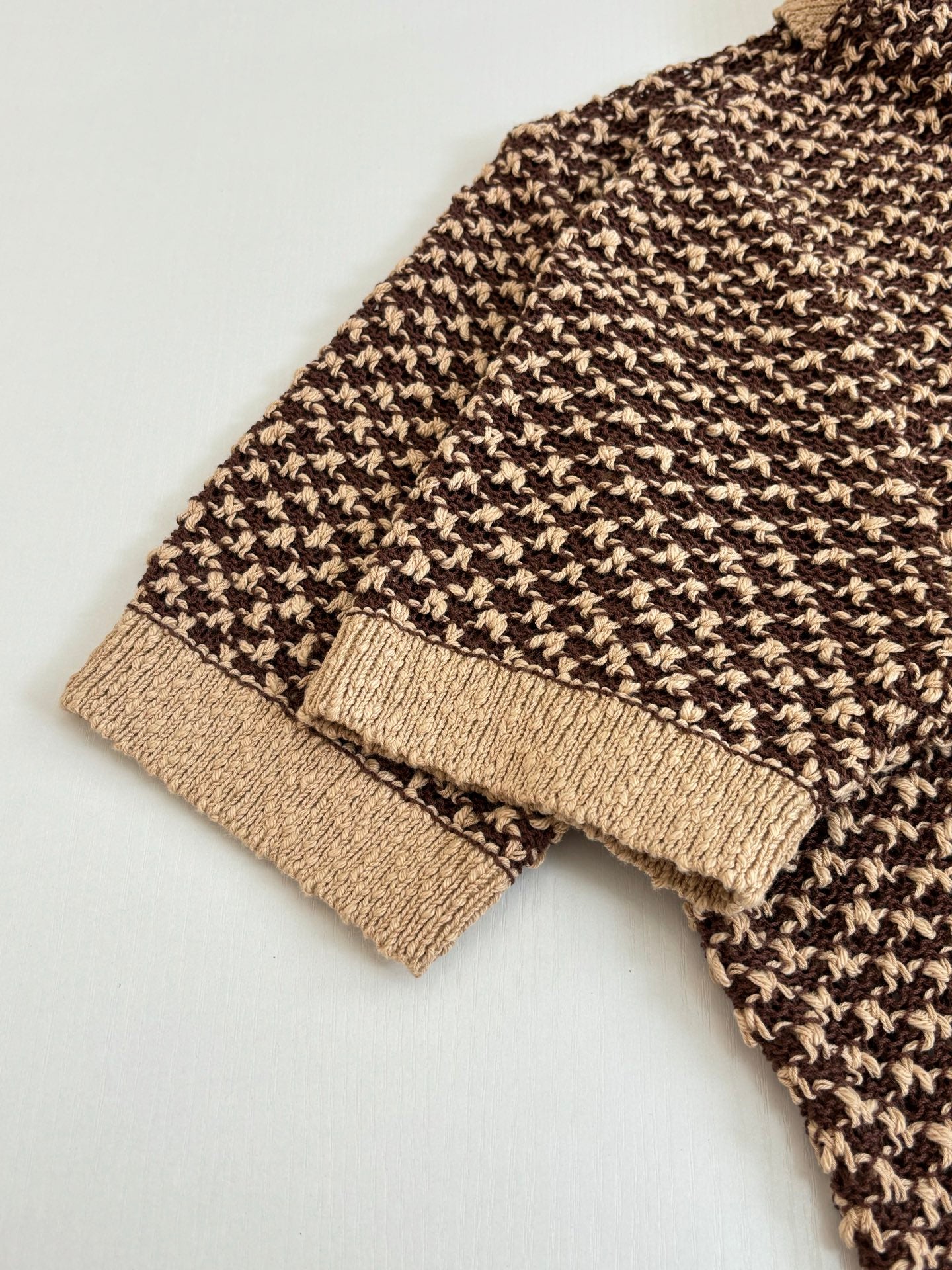 Knit polo shirt hem and cuff detail with tan rib trim and brown patterned knit