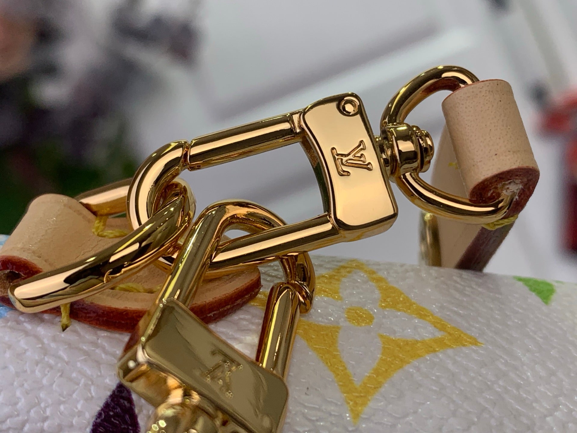Gold-tone clasp and chain hardware on a white Louis Vuitton crossbody bag