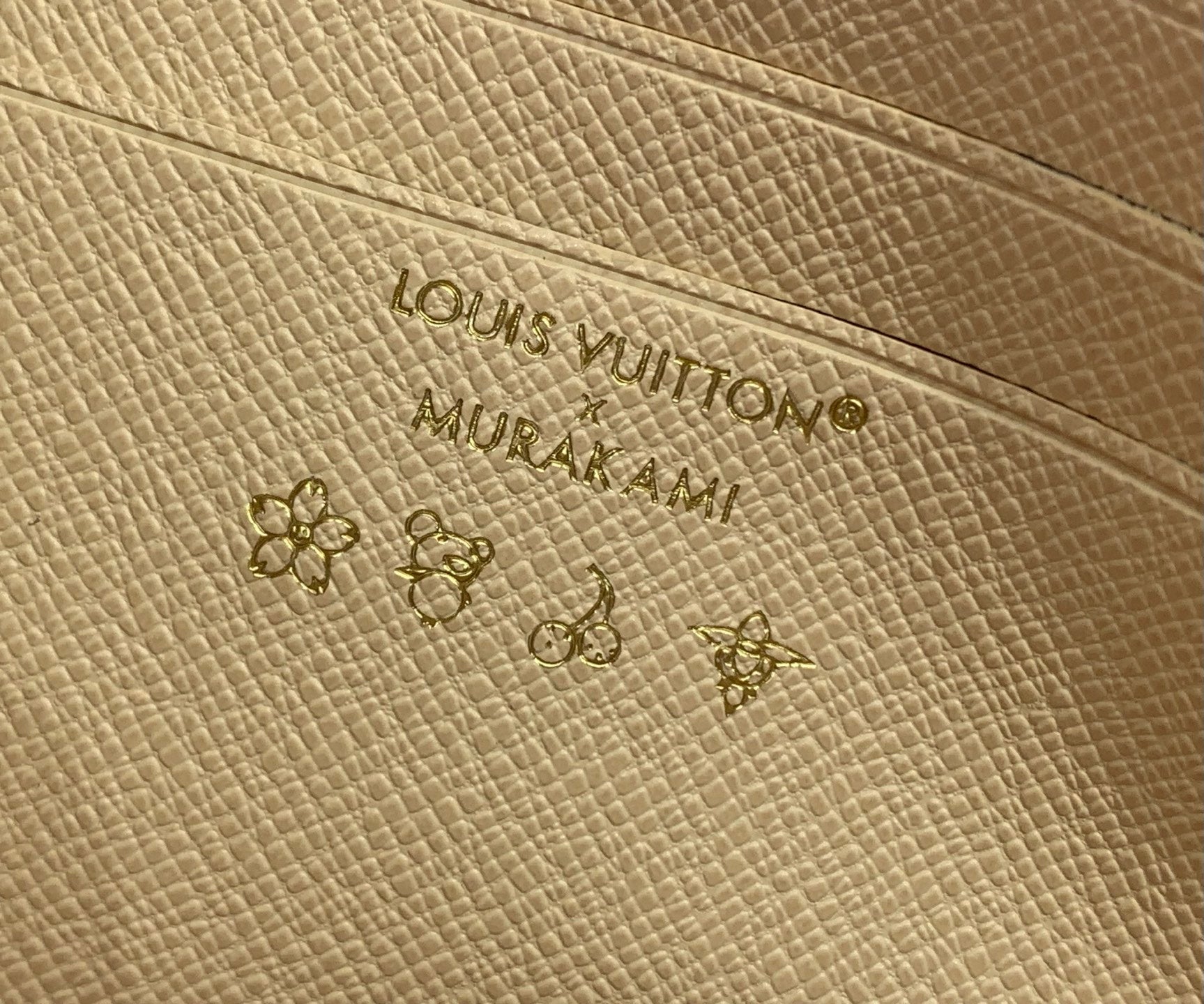 Louis Vuitton embossed logo on beige leather base with small multicolor monogram motifs