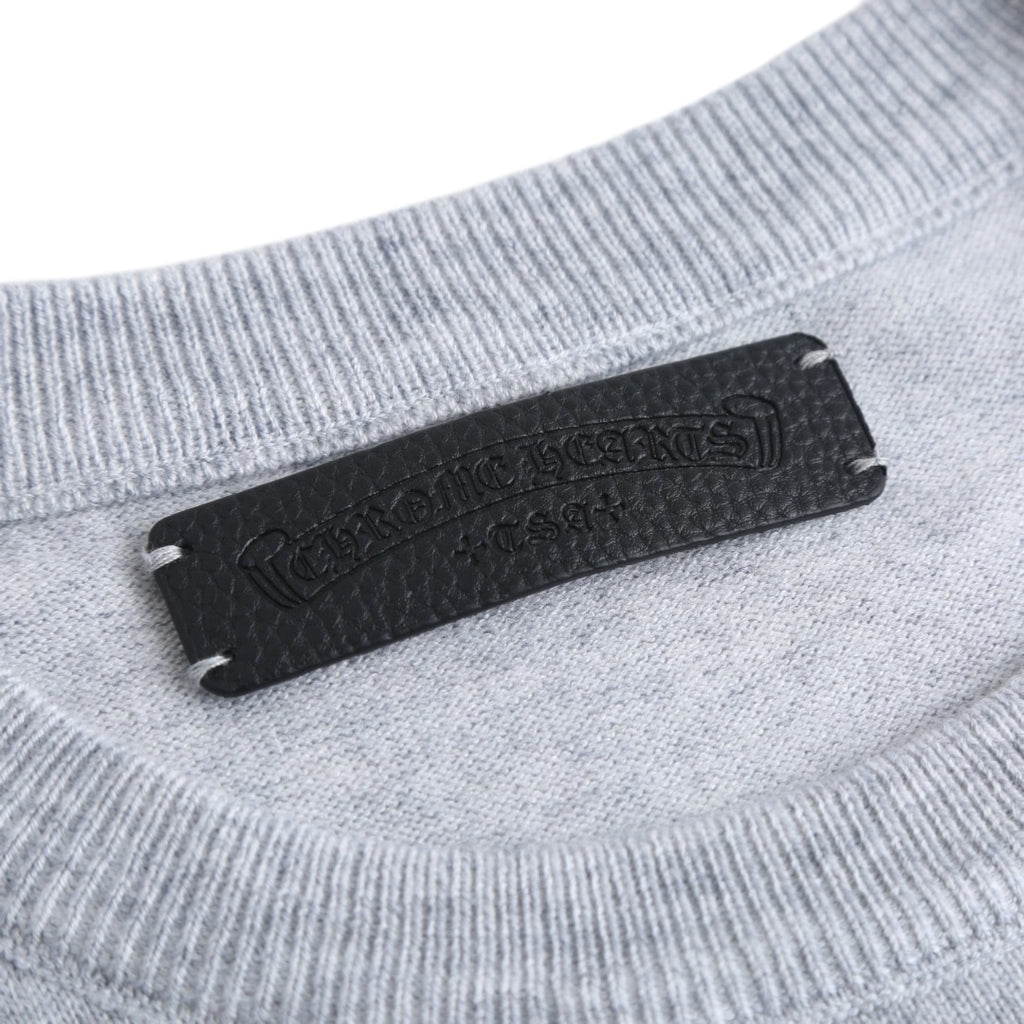 Black brand label on the neckline of a light gray crewneck sweatshirt.