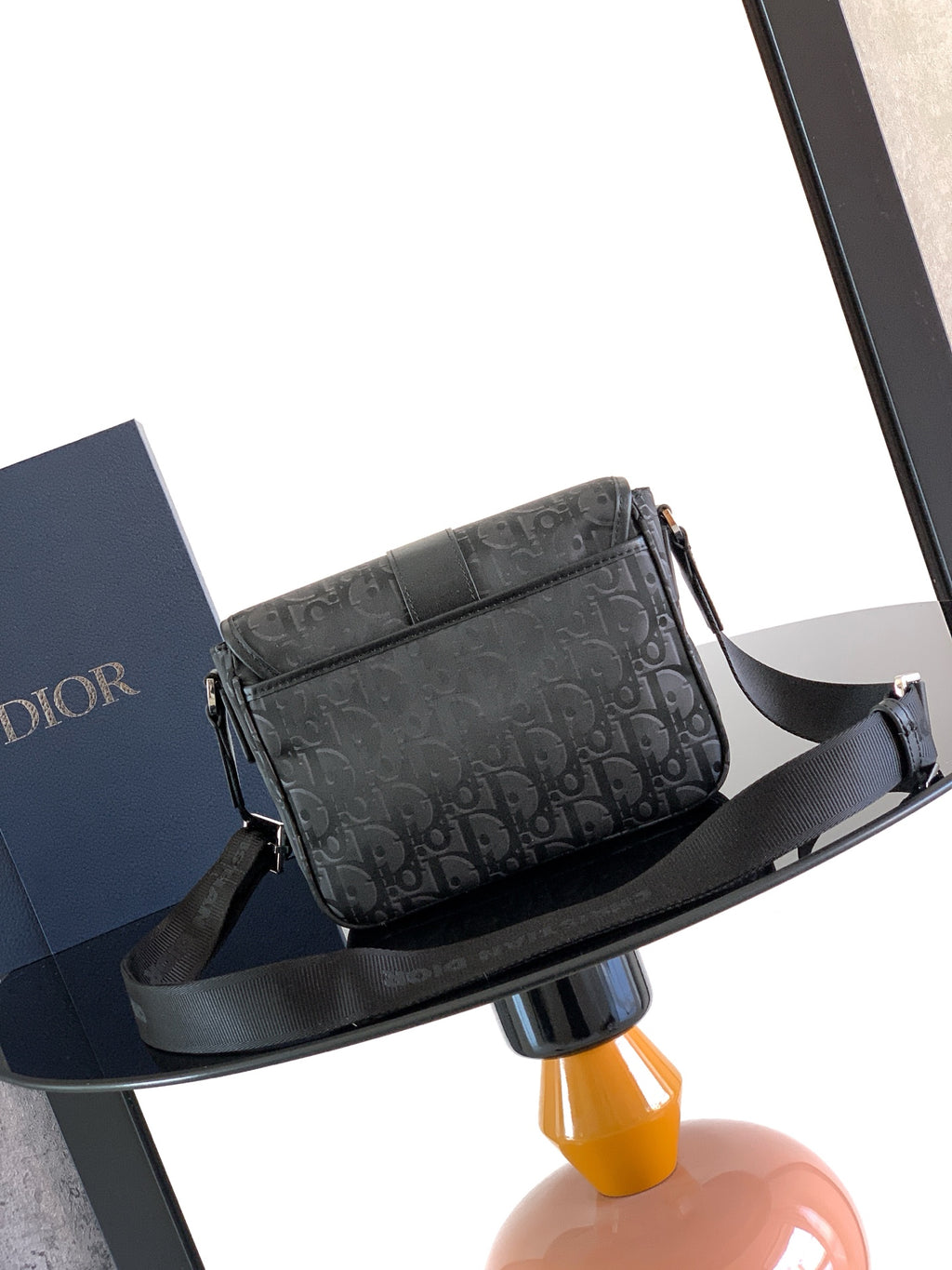 Dior bag with dark Dior Oblique pattern, front flap, and black shoulder strap