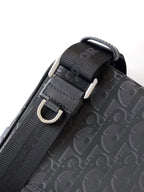 Dior bag strap close-up with black webbing, metal buckle, and dark Oblique pattern