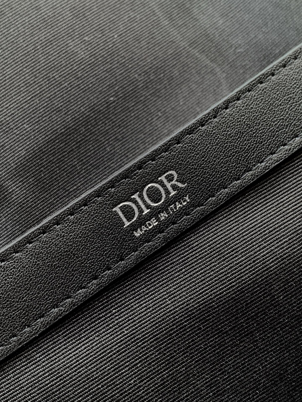 Dior bag detail with embossed DIOR lettering on black leather trim
