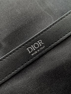 Dior bag detail with embossed DIOR lettering on black leather trim