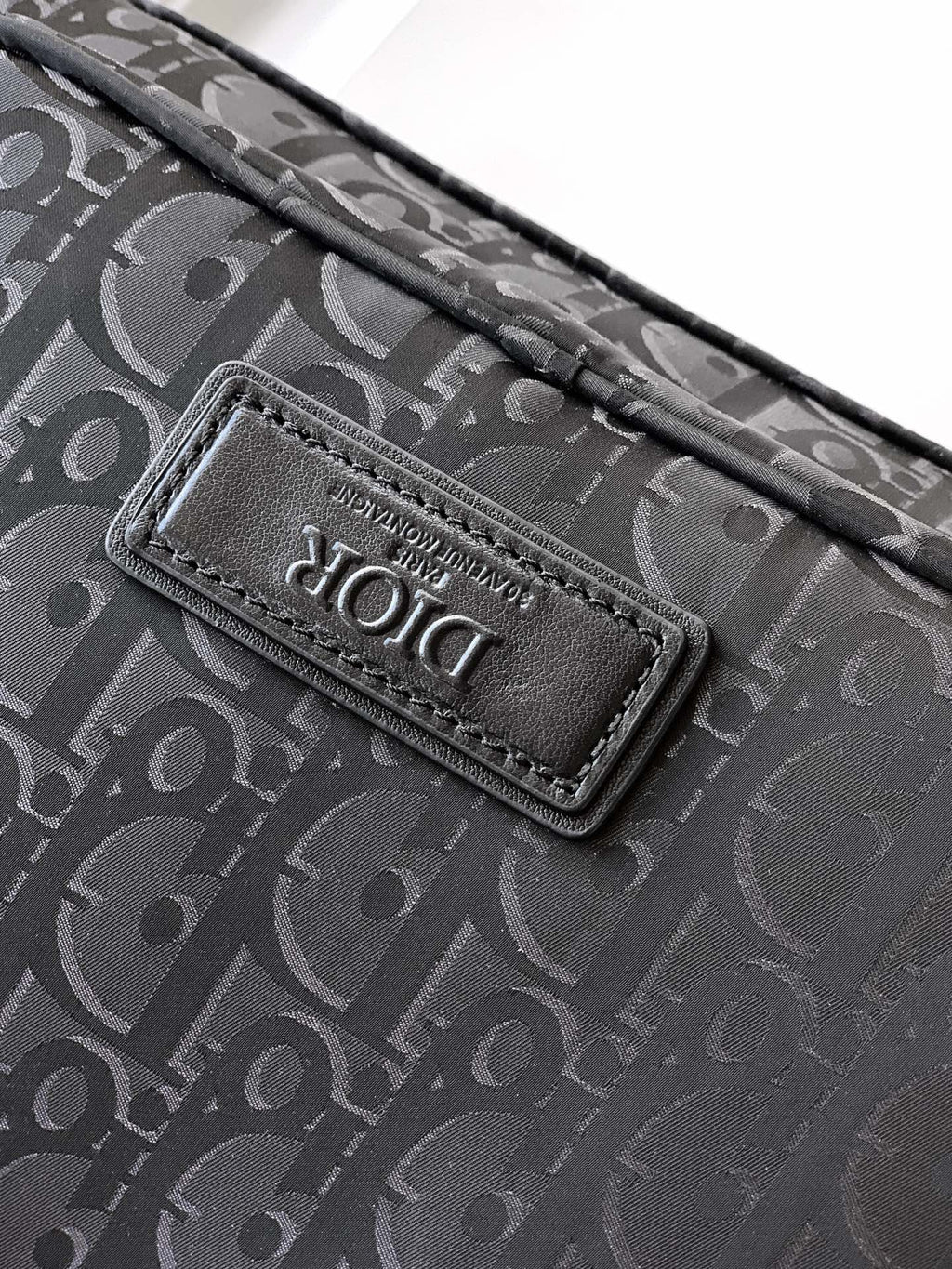 Dior monogram bag logo patch on dark fabric, stitched onto the flap