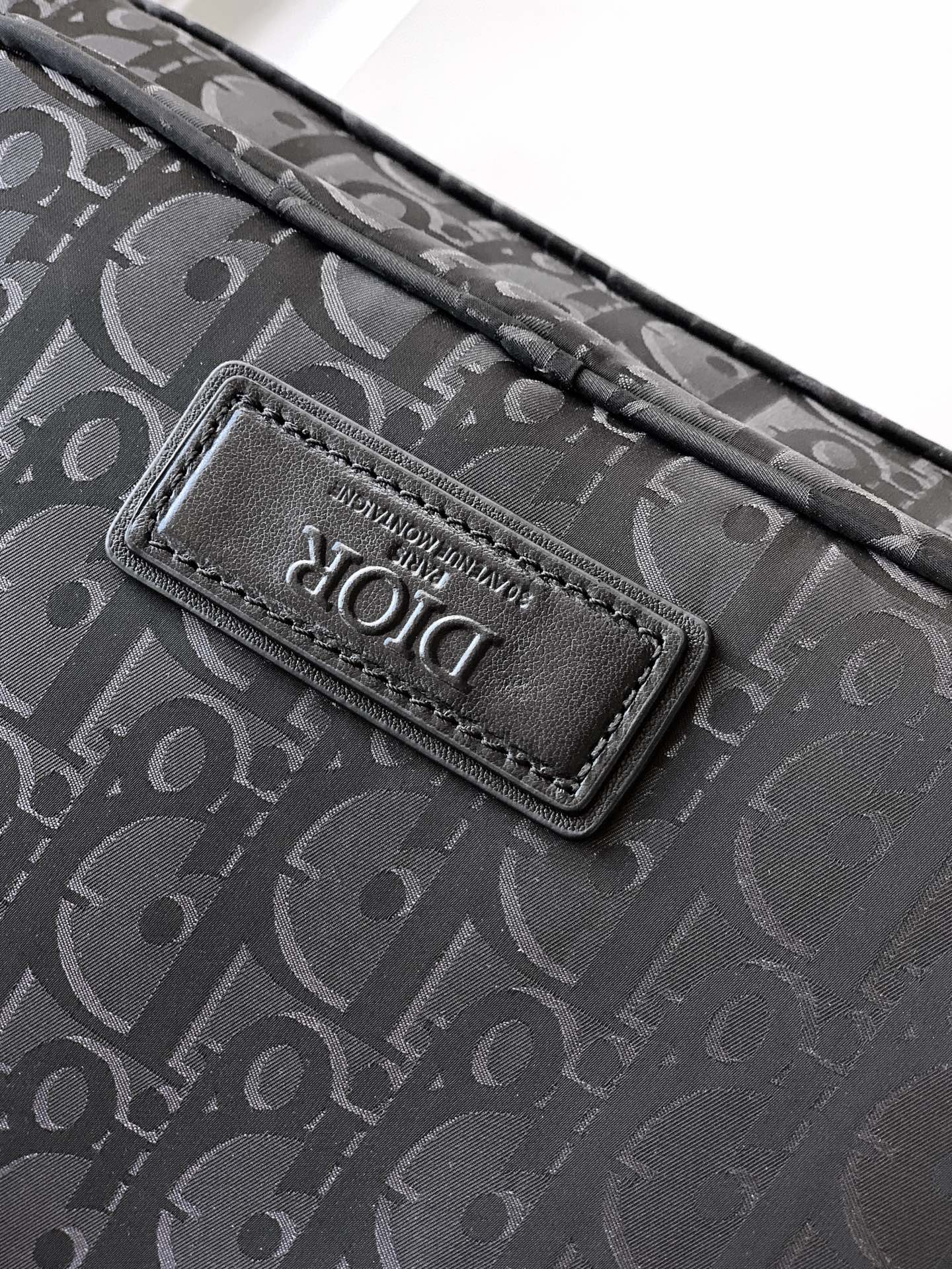 Dior monogram bag logo patch on dark fabric, stitched onto the flap