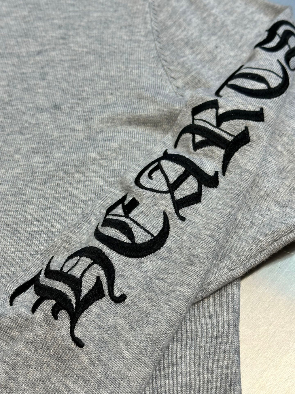 Light gray sweatshirt with large black graphic lettering along the sleeve