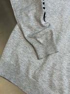 Light gray heather sweatshirt sleeve with black graphic detail near the cuff