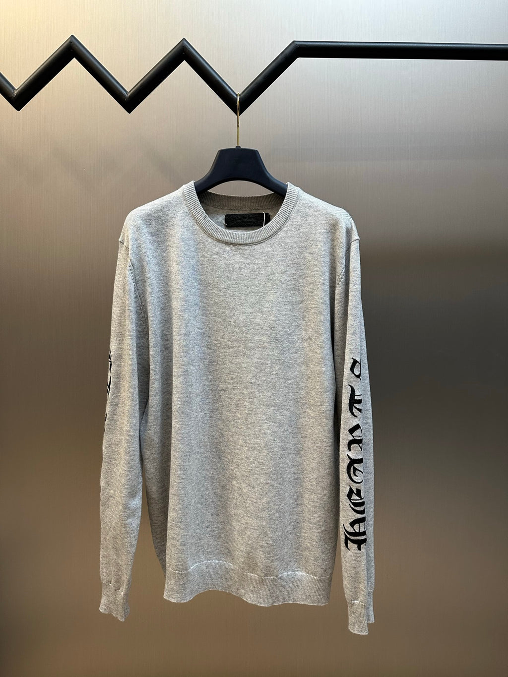 Light gray heather crewneck long-sleeve sweatshirt on hanger with black sleeve graphic