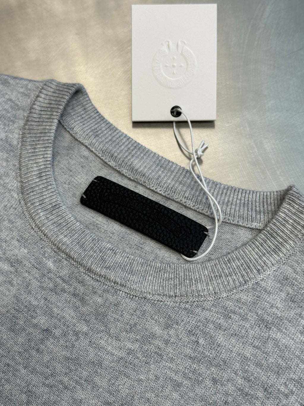 Light gray ribbed crewneck sweatshirt with collar cutout and black backing