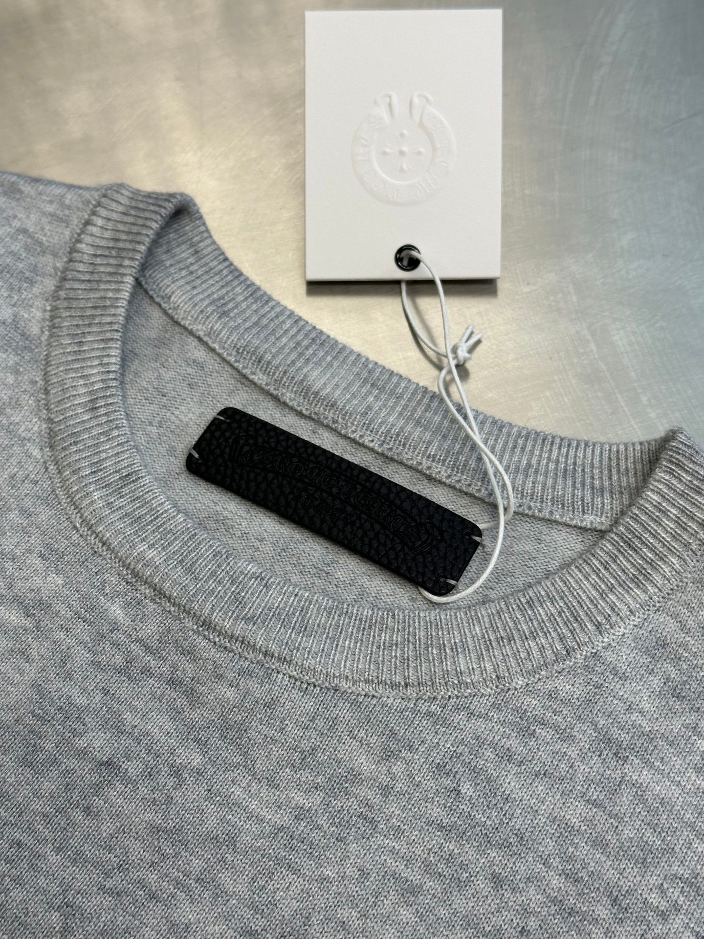 Light gray ribbed crewneck sweatshirt with collar cutout and black backing