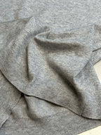 Light gray heather sweatshirt folded with ribbed collar and cuffs visible