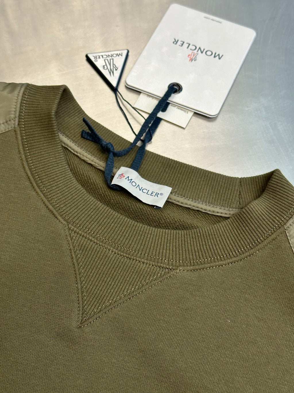 Moncler olive green crew-neck sweatshirt with ribbed collar and blue logo tag