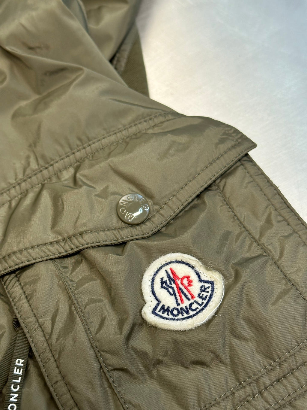 Moncler logo patch on olive green quilted shoulder, with snap button