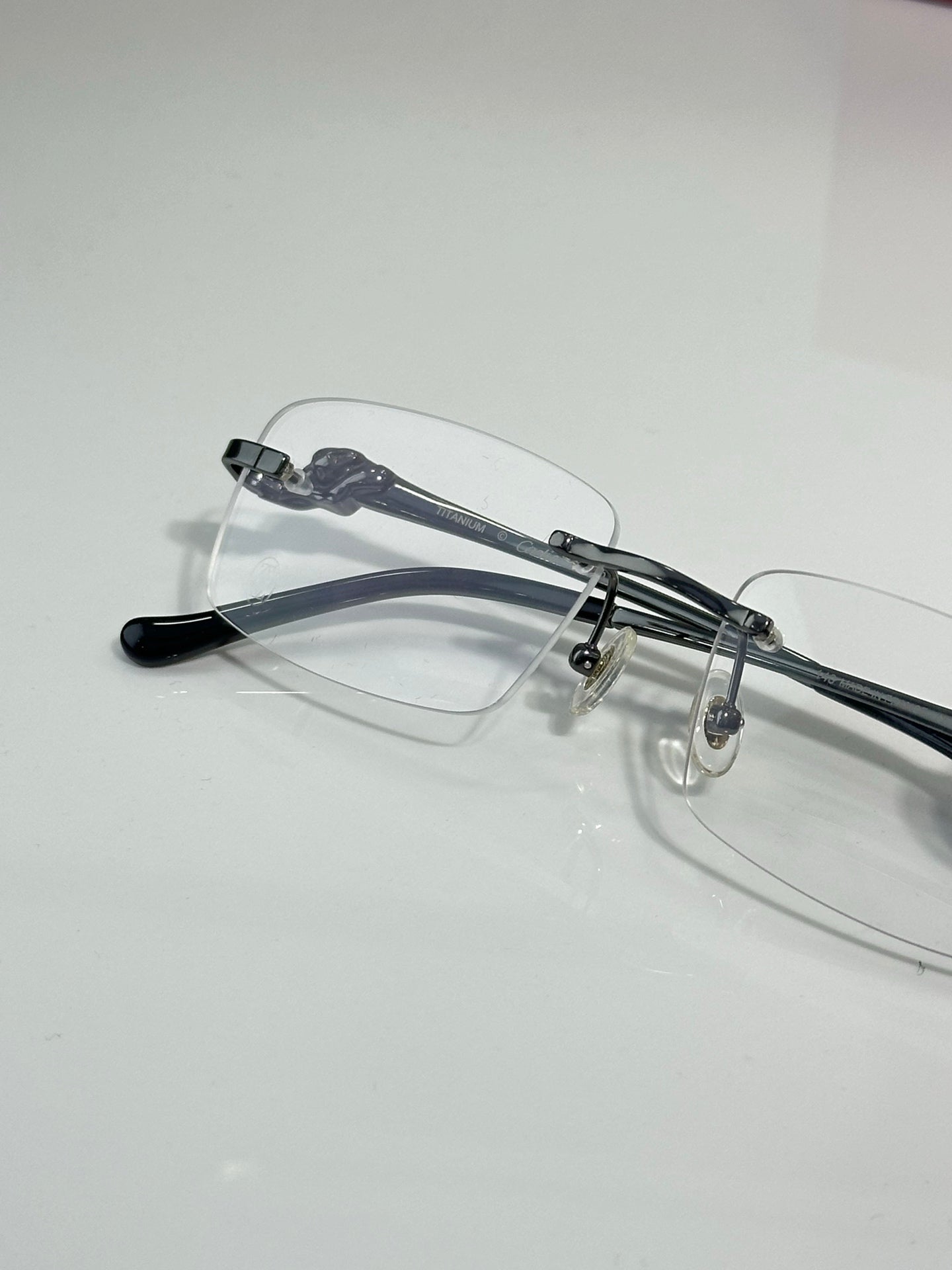 Cartier eyeglasses close-up with clear lenses, dark arms and metal bridge detail.