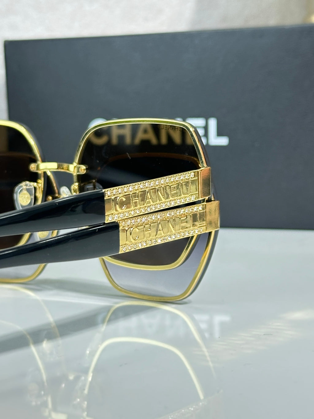 Chanel glasses close-up with gold frames and blue-green lenses