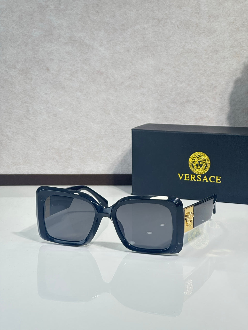 Square Versace sunglasses, dark blue frame with gray tinted lenses.