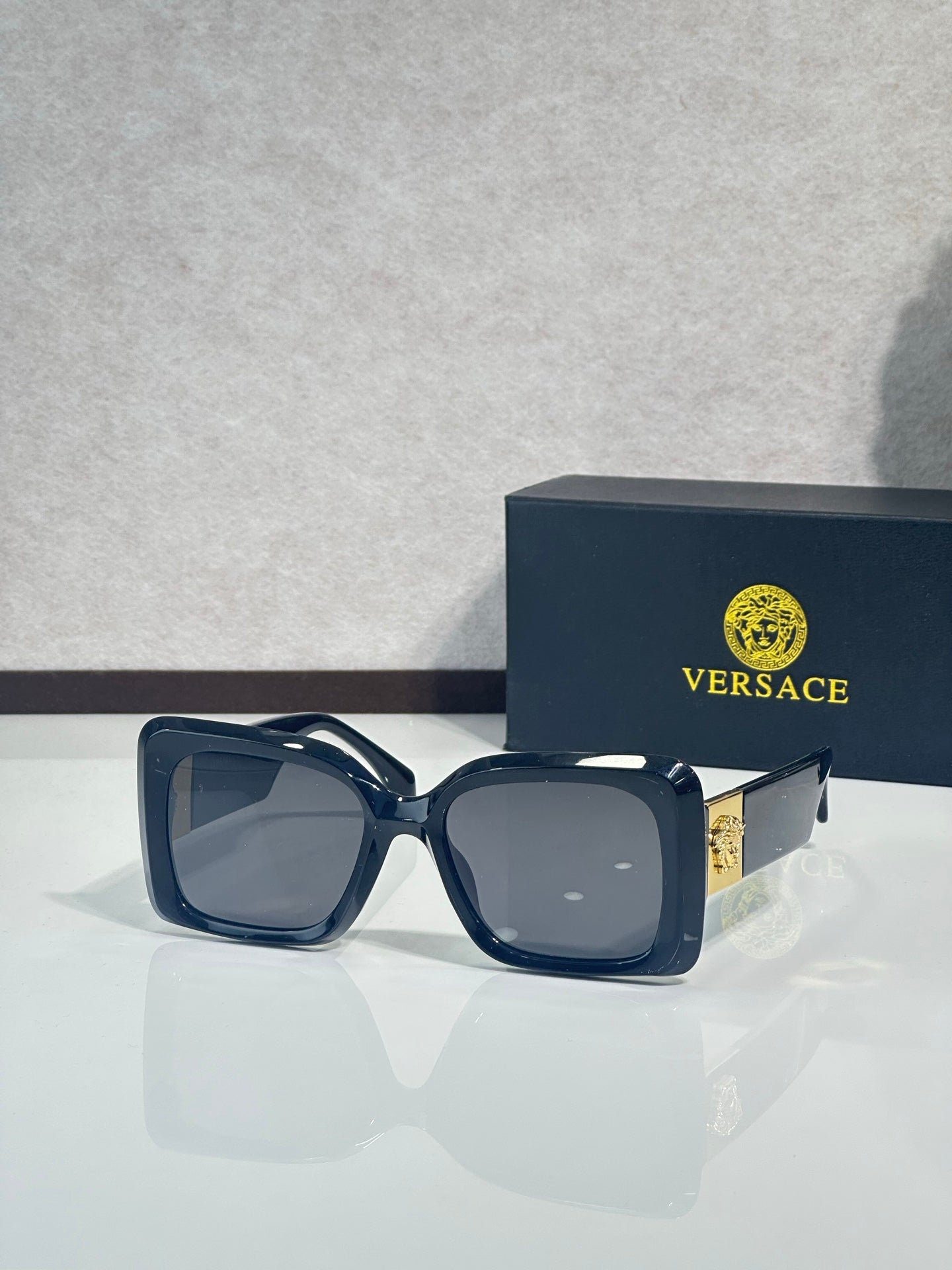 Square Versace sunglasses, dark blue frame with gray tinted lenses.