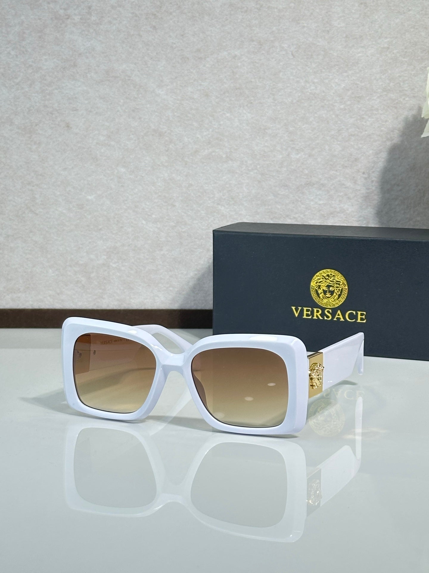 Square Versace sunglasses, white frame with beige-tinted lenses.