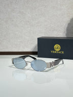 Oval sunglasses with light blue lenses, silver-toned frame, gold logo hardware.