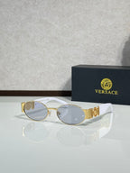 Oval sunglasses with gray-tinted lenses, gold temple details, clear lens tint.