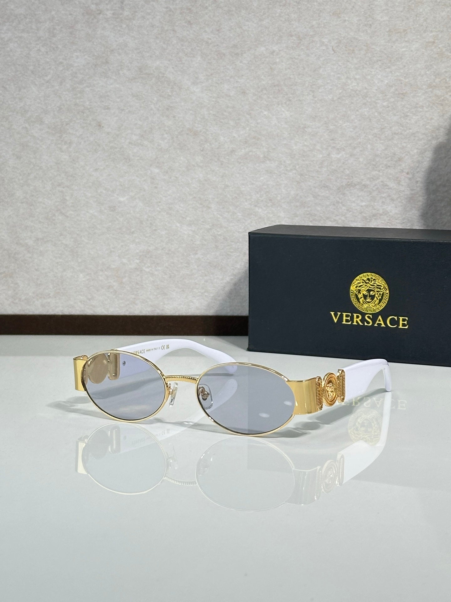 Oval sunglasses with gray-tinted lenses, gold temple details, clear lens tint.