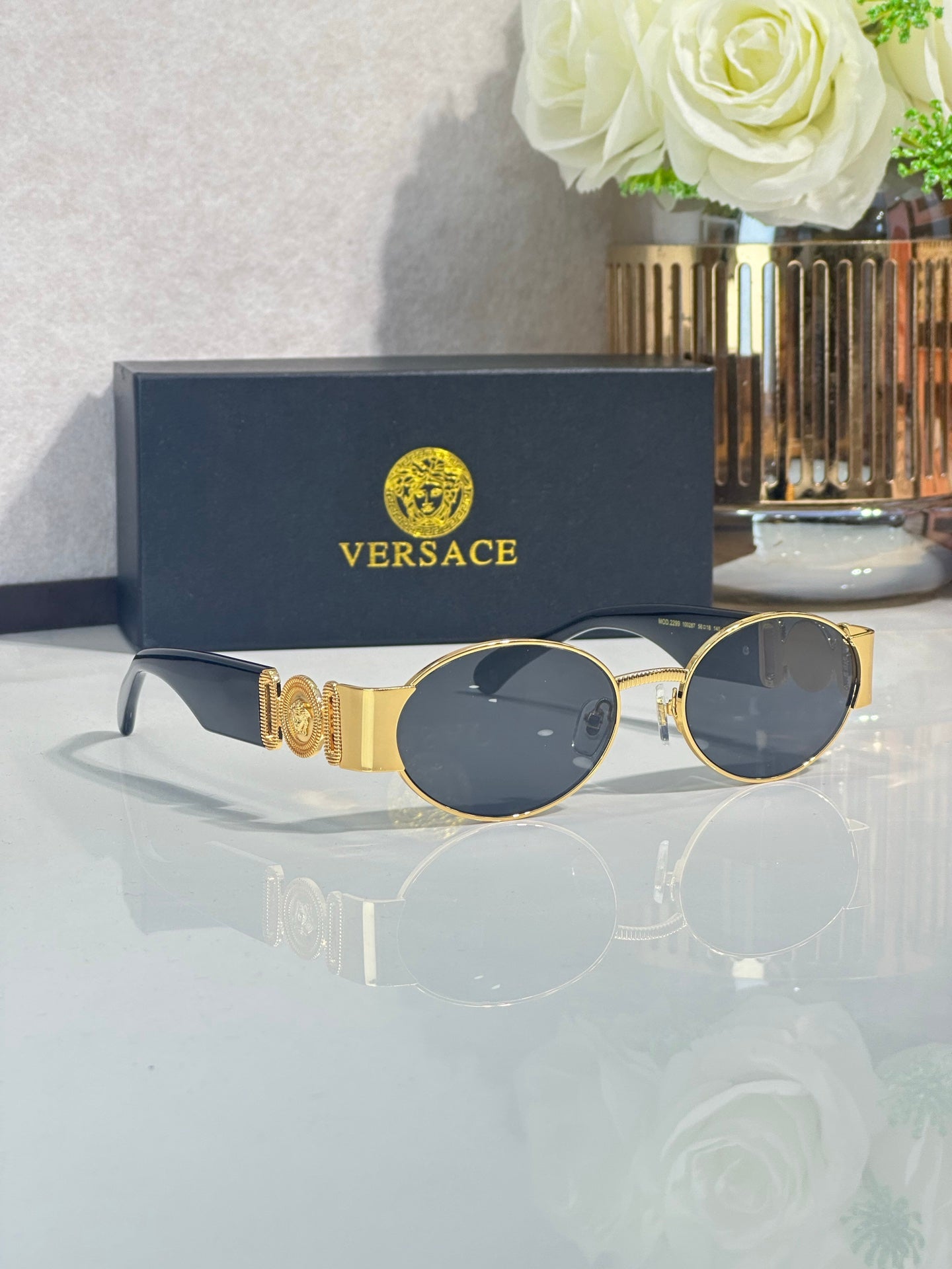 Oval sunglasses with dark blue lenses, gold temples, round-oval lens shape.