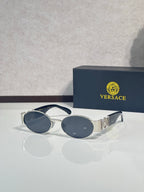 Oval sunglasses with dark blue lenses, black temples, gold hardware accents.