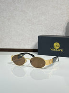 Oval sunglasses with brown-tinted lenses, gold temple details, classic metal frame.