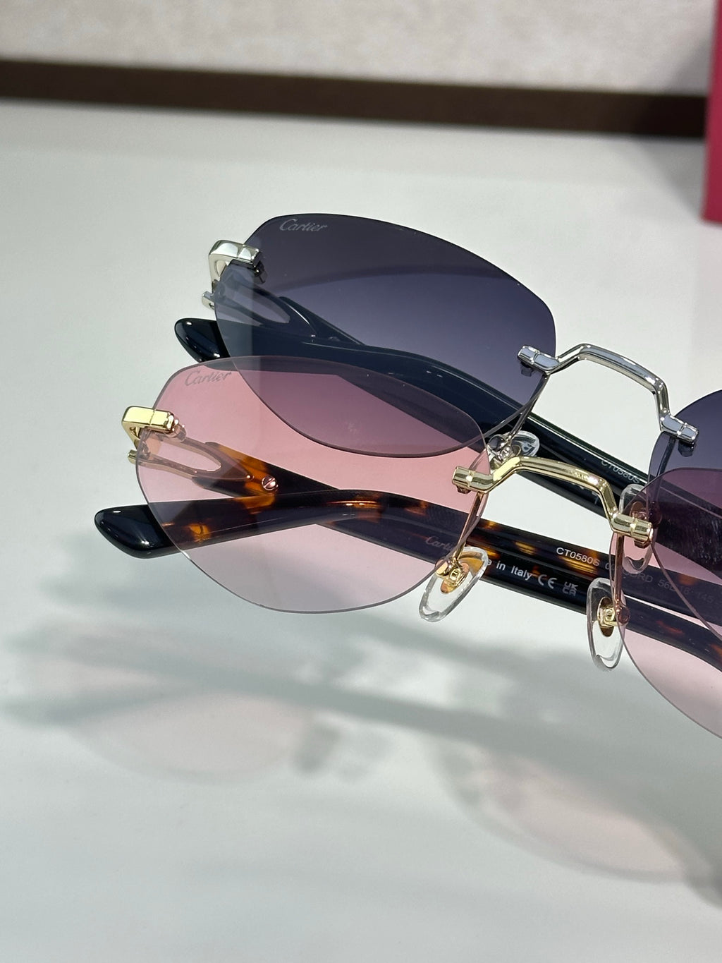Cartier sunglasses with dark navy frame, gold details, and pink-to-blue lenses