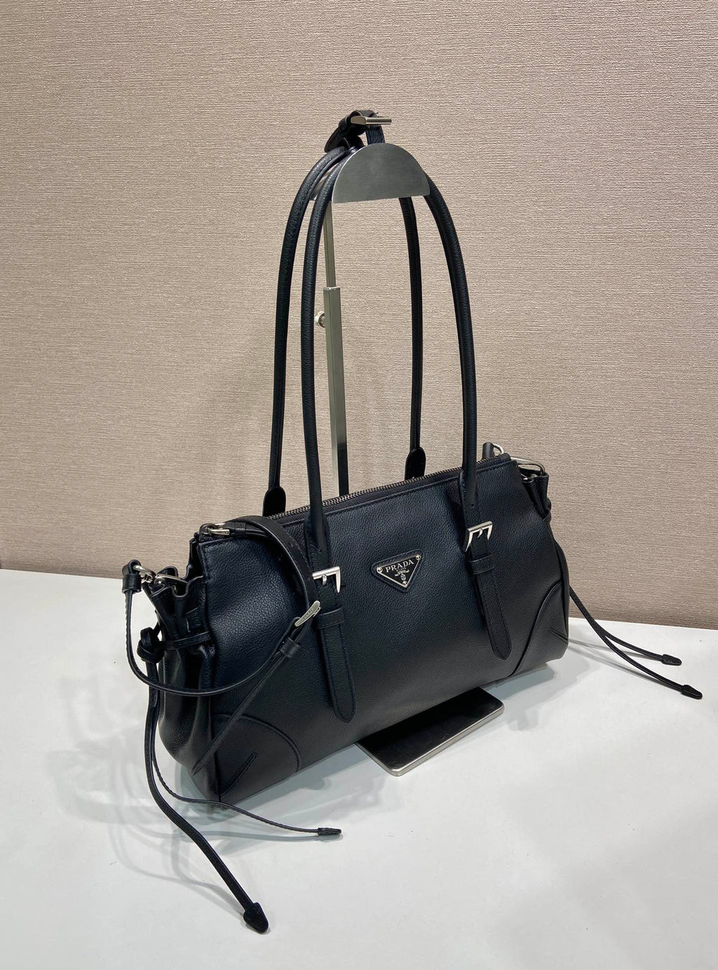 Prada handbag in dark blue leather with top handles, crossbody strap, and logo