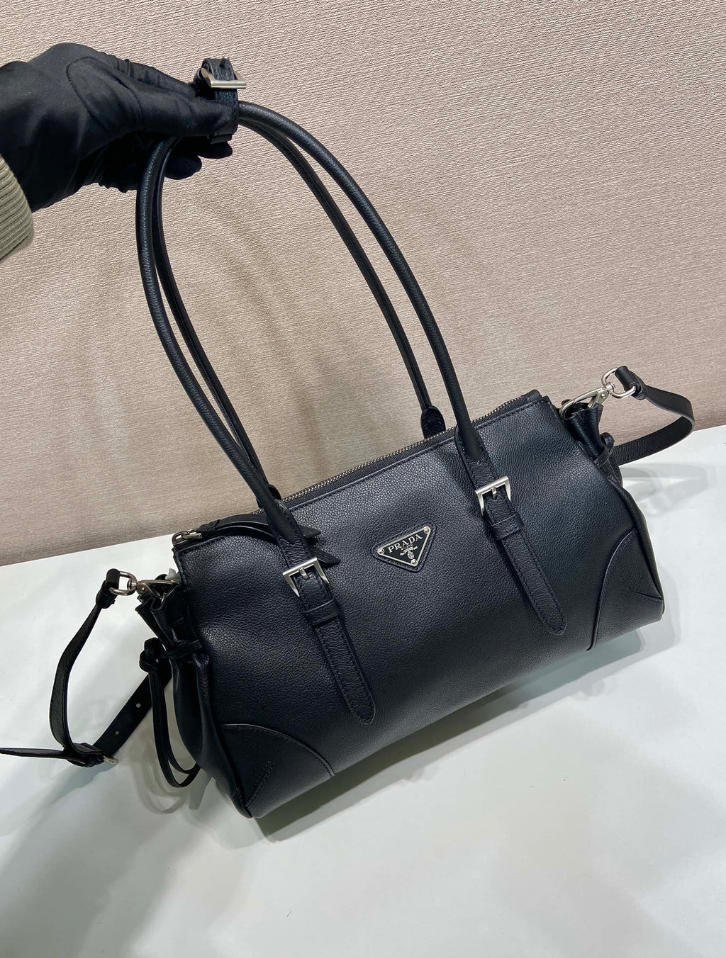 Prada handbag close view with top handles and front buckles in dark blue leather