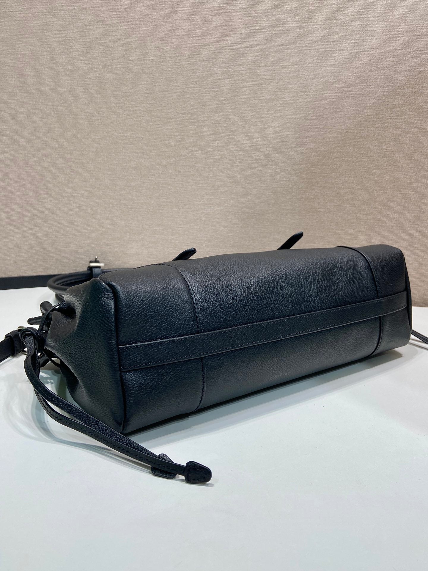 Prada handbag in dark blue leather with long shoulder strap and rolled top silhouette