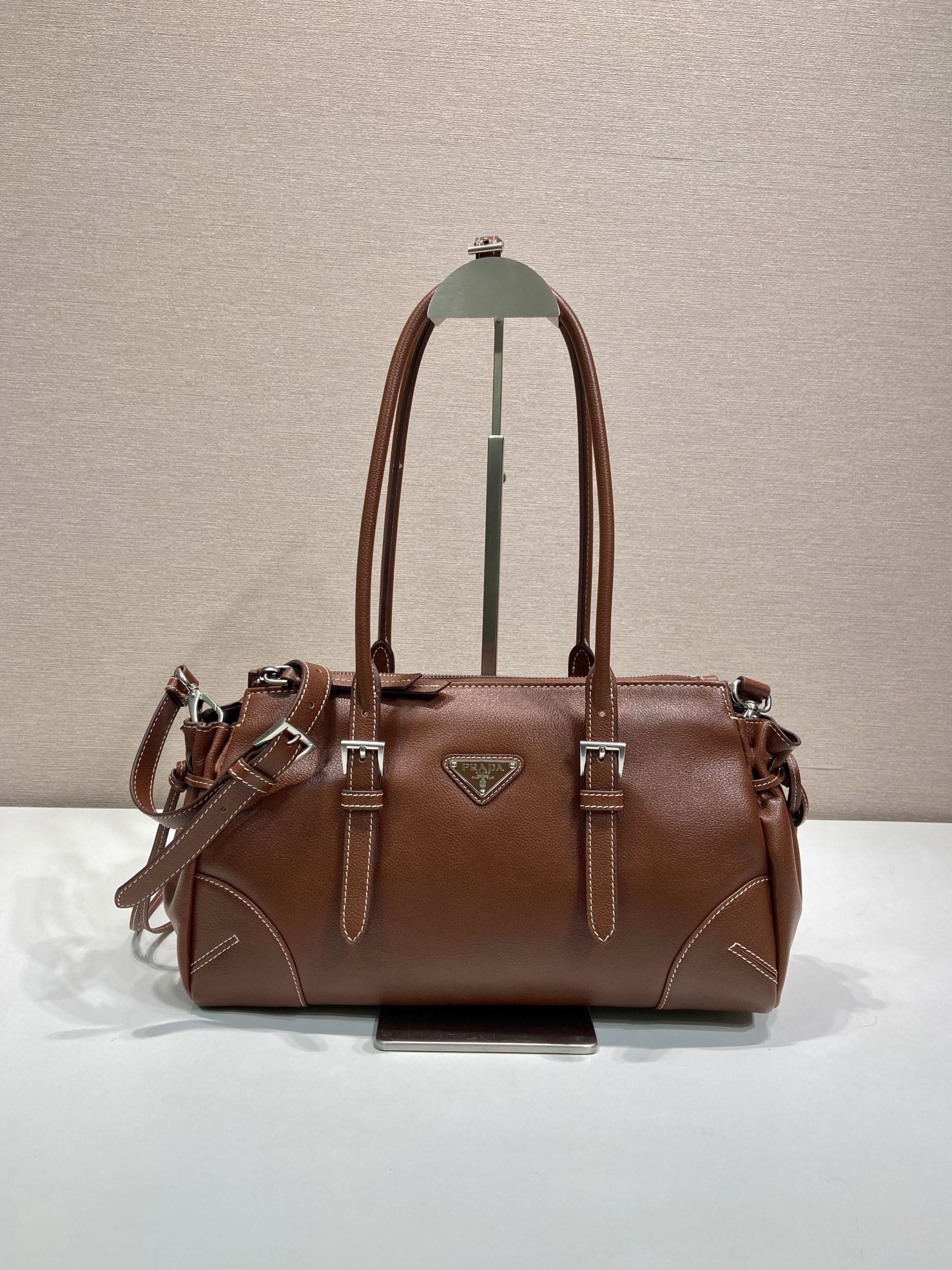 Prada brown leather tote bag with top handles, logo triangle, and silver hardware